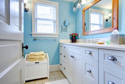 Blue and white bathroom with lots of storage space with open door.