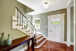 Entrance hallway with staircase and table. View of steps with wrought iron railings