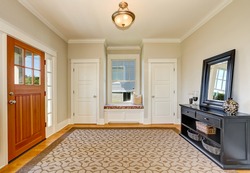 Nicely decorated hallway interior with soft beige walls, Black cabinet with mirror and wicker baskets and comfortable window seat between two closets. Northwest, USA