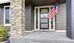 Column porch of luxurious house with American flag.  Northwest, USA