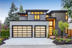Luxurious new construction home in Bellevue, WA. Modern style home boasts two car garage spaces with glass folding doors illuminated by scones. Northwest, USA
