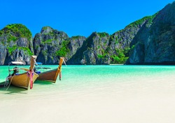 Famous Maya Bay beach at Ko Phi Phi Leh Island with two traditional longtail taxi boats mooring and steep limestone hills in background. Main Thailand tourist attraction, Krabi Province, Andaman Sea