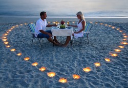 beautiful romantic supper with candles heart on the sand sea beach - a couple of newlyweds or lovers
