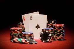Poker chips and playing cards on red background
