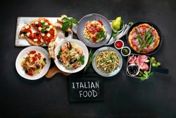 Italian food  on dark background with pasta, pizza, top view, copy space