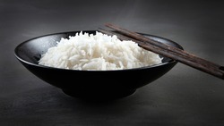 Hot boiled jasmin rice with steam on black background