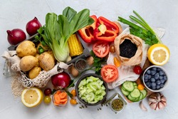 Selection of fresh raw vegetables, fruits and beans on light gray background. Organic food concept. Top view
