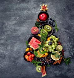 Christmas tree made of fruits on dark background. New Year Holidays concept. Top view, flat lay, copy space