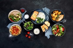 Set of various main dishes. Different healthy main courses, meat and fish dishes, pasta, salads, sauces, bread and vegetables on a dark background. Top view.