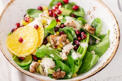 Fresh salad with chicken, orange and pomegranate seeds. Healthy diet food concept. View from above
