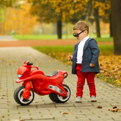 cute little biker on road with motorcycle. Young boy on toy motorcycle 
