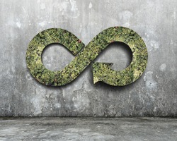 Green circular economy concept. Arrow infinity symbol with grass on concrete wall.