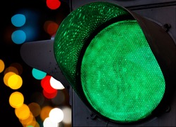 Green traffic light with colorful unfocused lights on a background