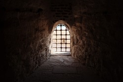Window with bars in the old fortress, dark architectural background