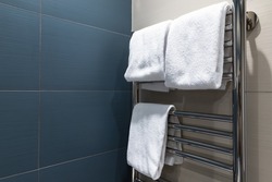 White towels are dried on a heated towel rail in the bathroom