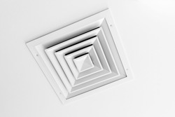 White ceiling ventilation grille with square diffusors, close up photo