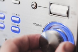Male hand is on a volume control knob, close up-photo with selective soft focus