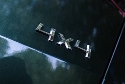 All wheel drive sign, shiny metallic text 4x4 on a modern SUV car back, close up photo