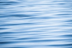 Blue water surface with a pattern of soft waves, background photo texture