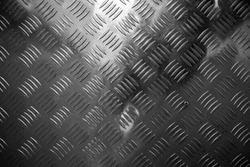 Dark shining metal floor surface with industrial diamond plate relief pattern