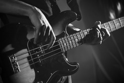 Closeup photo of bass guitar player hands, soft selective focus, live music theme, black and white