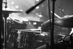 Black and white live music background, drummer plays with drumsticks on rock drum set. Closeup photo with soft selective focus