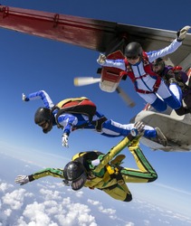 Four girls parachutists jump out of an airplane.