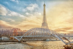 Eiffel Tower and a bridge over the Seine River at sunset in Paris, France. Romantic travel background.