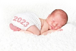 Happy New Year 2023. Newborn baby girl asleep on a white blanket. 