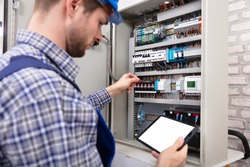 Technician Holding Digital Tablet With Blank Screen In Front Of Fuse Box