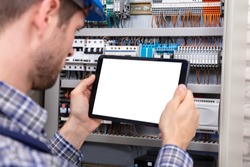 Technician Holding Digital Tablet With Blank Screen In Front Of Fuse Box