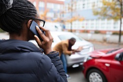 Woman Calling For Assistance In Front Of Man Inspecting Damaged Car On Road