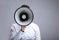Man Doing Announcement Using Megaphone Against Gray Background