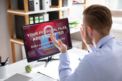 Worried Businessman Looking At Computer With Ransomware Word On The Screen At The Workplace
