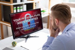 Worried Businessman Looking At Computer With Ransomware Word On The Screen At The Workplace