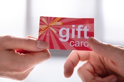 Close-up Of Female Hand Giving Gift Card To Her Male Partner
