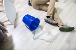 Mature Man Falling On Wet Floor In Front Spilled Bucket Of Water At Home