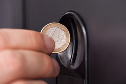 Close-up of human hand inserting coin in vending machine