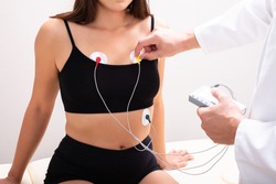 Doctor Applying Holter Monitor Device On Woman's Body For Daily Monitoring Of An Electrocardiogram