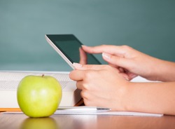 Student using digital tablet beside green apple while studying