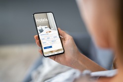 Close-up Of A Person Holding A Smart Phone Using Online Low Prices Hotels Application