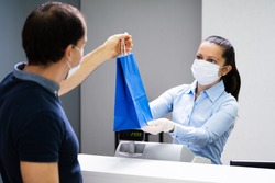 Cashier In Retail Shop Or Store At Counter Wearing Face Mask