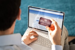 Man's Hand Holding VIP Member Card While Using Laptop