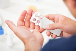 Cropped image of man taking pill out from blister pack at home