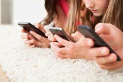 Cropped image of family using smart phones on rug at home