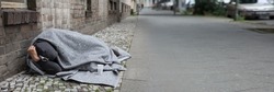 Homeless Man Covered With Blanket Sleeping On Street In City