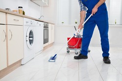 Close-up Of Worker Cleaning Floor With Mop In Kitchen Room