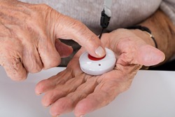 Close-up Of Senior Woman Pressing Alarm Button For Emergency