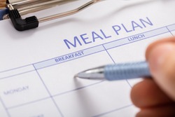 Close-up Of Person Hand Filling Meal Plan Form