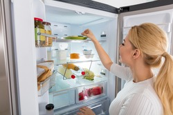 Close-up Of Young Woman Taking Food To Eat From Refrigerator